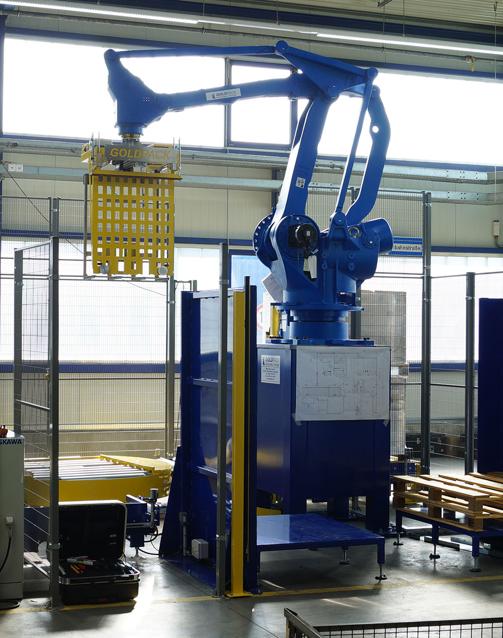 Automatisierte Verpackungsanlage mit Greif-Roboter und Palettenstretchwickler für effiziente Versandprozesse.