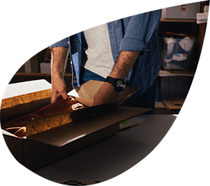 Person verpackt ein Produkt in einem nachhaltigen Karton als umweltfreundliche Verpackungslösung.